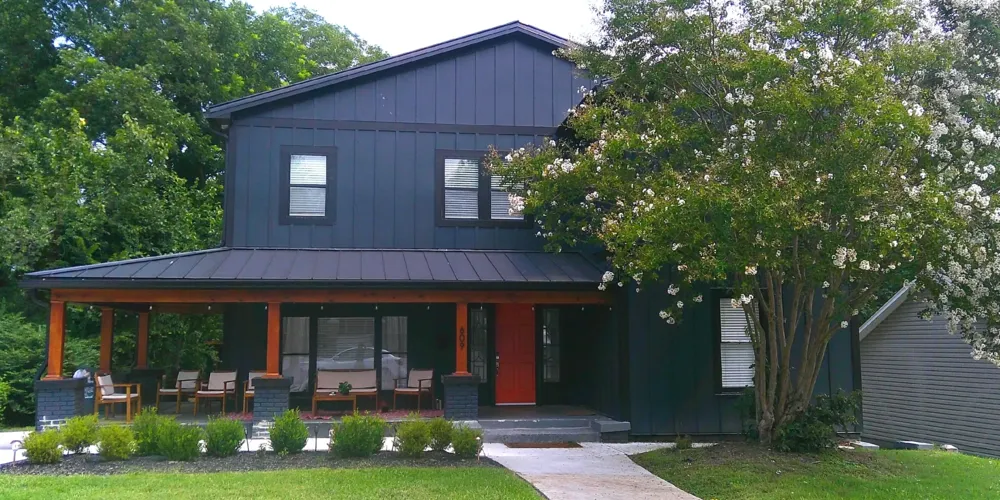 A renovated dark blue house with a red front door