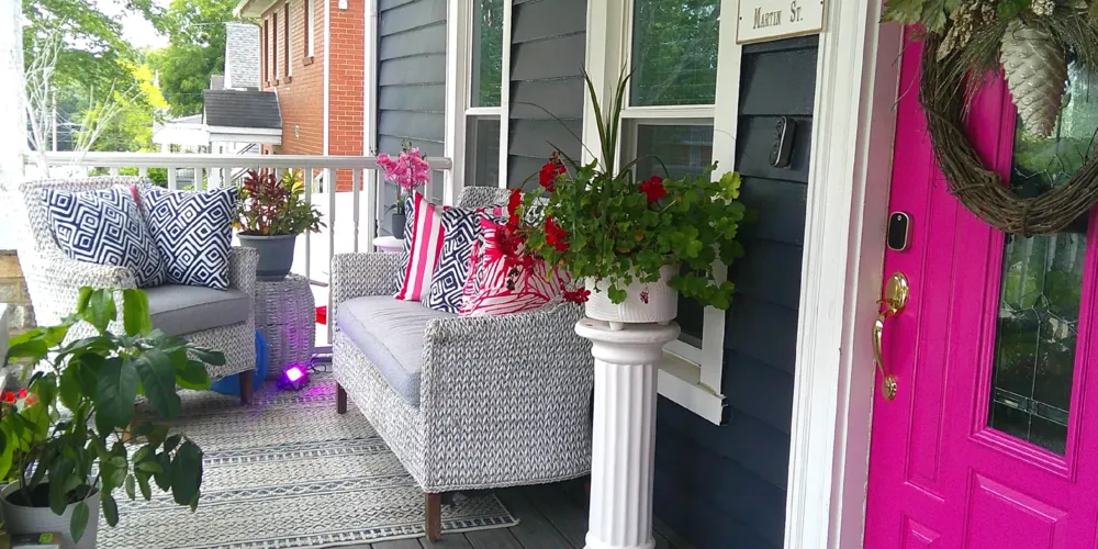 A decorated front porch with a patterned sofa and flowers